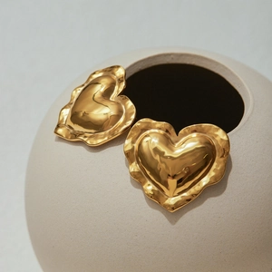 Macro shot of gold heart-shaped stud earring with a textured wavy edge design