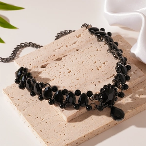 Detail of vintage black water-drop gemstone necklace on a beige stone display tray