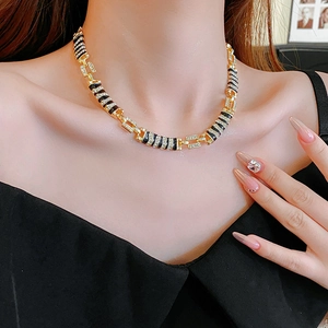 Close-up of elegant gold chain necklace with black inlay and sparkling crystals on model
