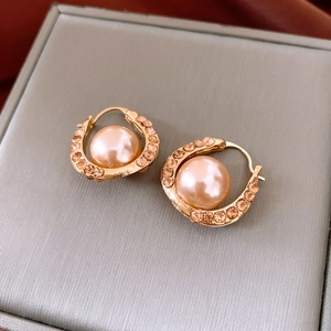 Macro view of gold U-shaped earring with pavé rhinestones and champagne faux pearl