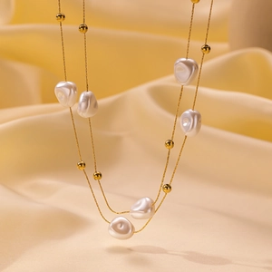 Collana a doppio strato in titanio dorato con perle barocche su sfondo di seta