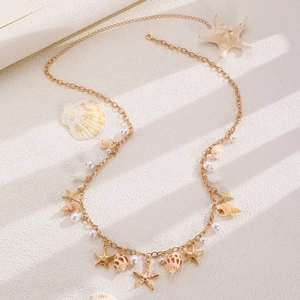 Detail of beach necklace with gold starfish, natural seashells and white pearls