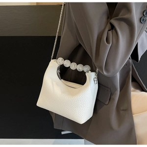 White textured leather dumpling bag with pearl handle shown on model in grey blazer