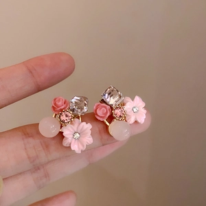 Dettaglio di orecchini a fiore rosa con effetto opale, strass e perni in argento