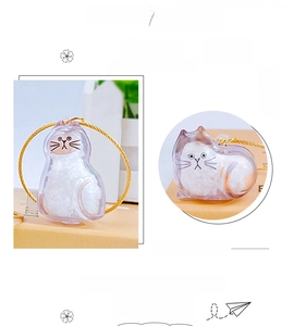 Detailed view of a cat-shaped transparent capsule pendant for storing fur with gold keychain