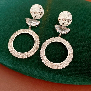 Detailed close-up of silver earrings with crystals on luxury green velvet padding