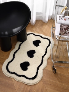 Detail of cloud-shaped cream rug with black hearts and wavy borders on wood floor