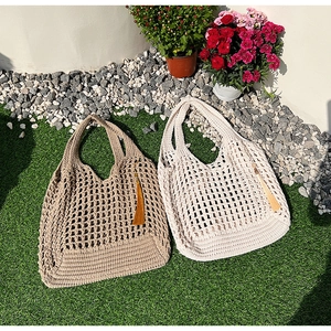 Close-up of large mesh hollow woven tote bag with tassel detail on green lawn