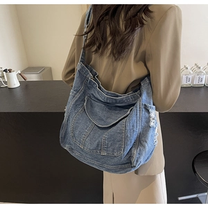 Détail du sac bandoulière en denim bleu avec franges sur un blazer de couleur kaki