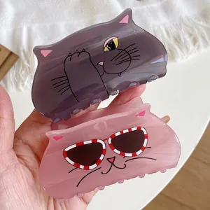 Handheld display of cute purple and pink acrylic cat hair claws with cartoon graphics