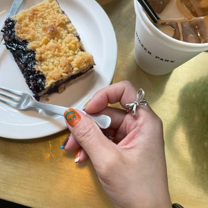 925 sterling silver bow ring for women shown in a cozy cafe afternoon tea setting