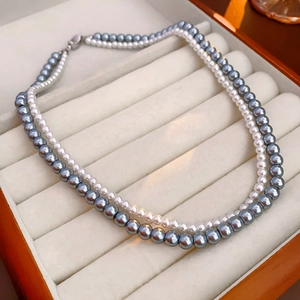 Detail view of double-layer necklace featuring grey and white pearls in a jewelry box