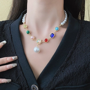 Close-up of pearl and colorful gemstone necklace with a drop pearl pendant on model