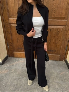 Detailed view of the black knitted two-piece set featuring smooth zip-up and drawstring pants