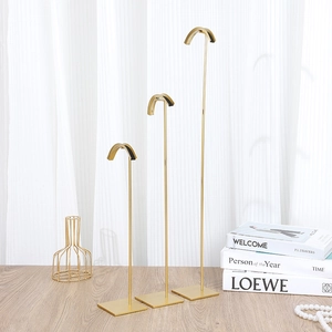 Three-tier gold metal jewelry display stands with square bases on a light wood surface