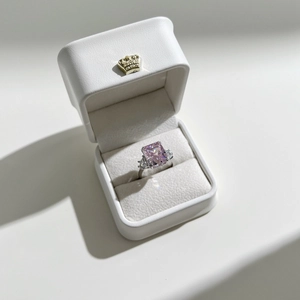Macro view of a silver S925 ring with a pink emerald-cut stone in a white leather box