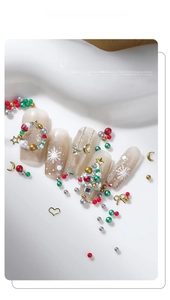 Macro view of Christmas nail art charms including metal snowflakes and colorful rhinestones