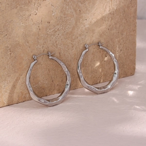 Detailed view of silver hoop earrings featuring geometric facets and hammered texture