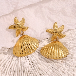 Detail shot of 18K gold plated starfish and shell earrings on white coral base
