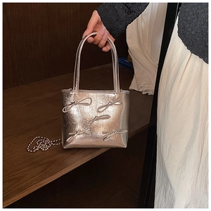 Close-up of silver mini handbag with metallic finish and 3D bow details and bead chain