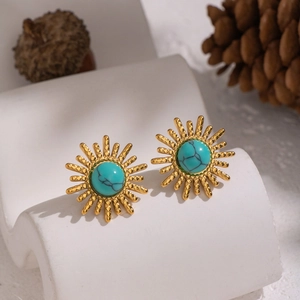 Vintage gold sun-shaped stud earrings with natural turquoise stone on textured white stand