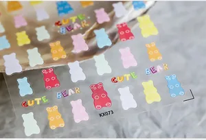 Macro shot of cute colorful bear nail stickers and letters on white textured paper