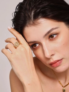 Detailed view of a gold hollow geometric ring with zircon stones on a model's hand