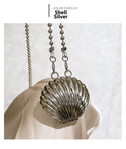 Detailed view of heart-shaped shell mini bag in silver finish on champagne silk background