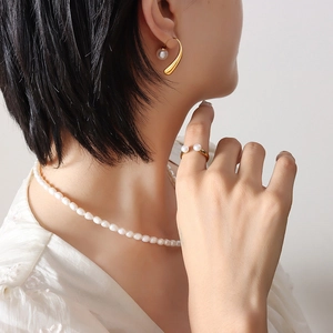 Elegant gold pearl jewelry set featuring necklace earrings and ring on a model
