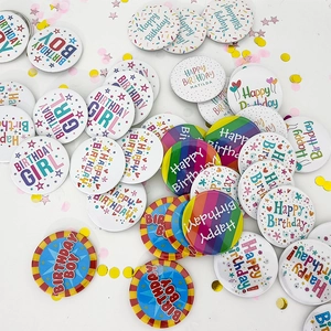 Colorful birthday party badges with various prints scattered on confetti background