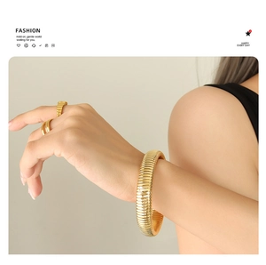 Detail of gold-plated tubogas bracelet and matching rings on a female model