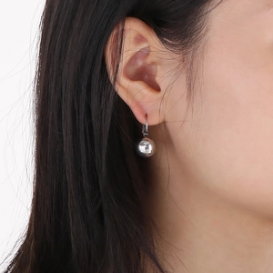 Close-up of a silver stainless steel ball drop earring with leverback clasp on model