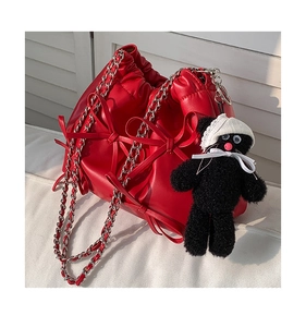 Detail of red pleated bucket bag with bow decorations and a cute plush charm
