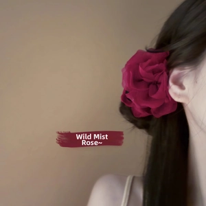 Dettaglio di una clip per capelli a forma di rosa in tessuto rosso scuro su un modello