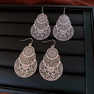 Detail of silver and rose gold hollow mandala flower earrings on black display