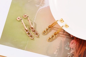 Macro shot of rose gold and gold drop earrings featuring sleek bar and cuban chain links