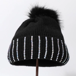 Détail du bonnet d'hiver noir avec strass colorés et pompon en fausse fourrure douce