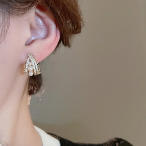 Close-up of elegant pearl and zircon earring worn on ear with French retro style design