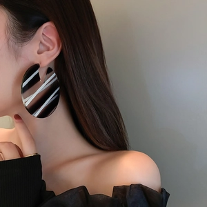 Close-up of model wearing round acrylic earrings with black and white striped patterns