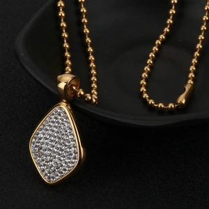 Gros plan d'une chaîne à billes dorée avec un pendentif losange étincelant de diamants