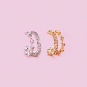 Detailed view of silver and gold ear cuffs with sparkling zircon stones on pink backdrop