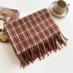 Detail of plaid scarf with tassels, orange and brown knit texture on a lifestyle setting