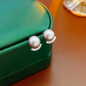 Close-up of elegant grey pearl stud earrings with sparkling cubic zirconia on a jewelry box