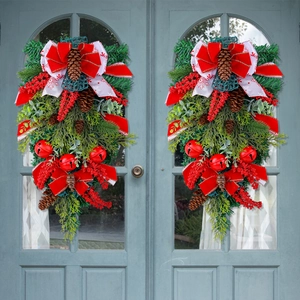 Christmas door swag with red bow pinecones bells and berries on green pine branches