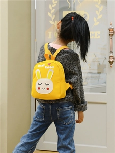 Close-up of a toddler wearing a yellow canvas rabbit backpack showing its size and fit