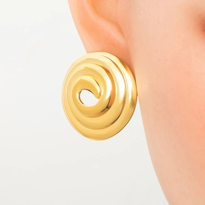 Close-up of golden hollow spiral earring worn by a model on clean white background