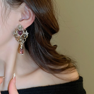Detailed side view of vintage Baroque earrings with purple heart stones on a model