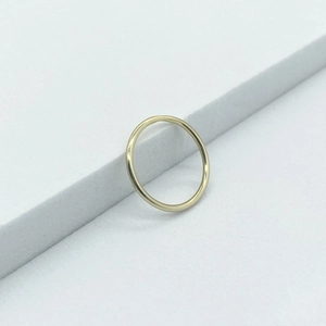 Minimalist S925 sterling silver toe ring with gold finish on a gray textured background