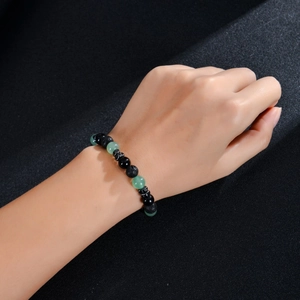 Macro detail of 8mm lava rock beads and green crystal skull bracelet on wrist