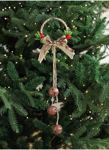 Detail of rustic brown bells with star cutouts, burlap bow and pine needles on Christmas tree